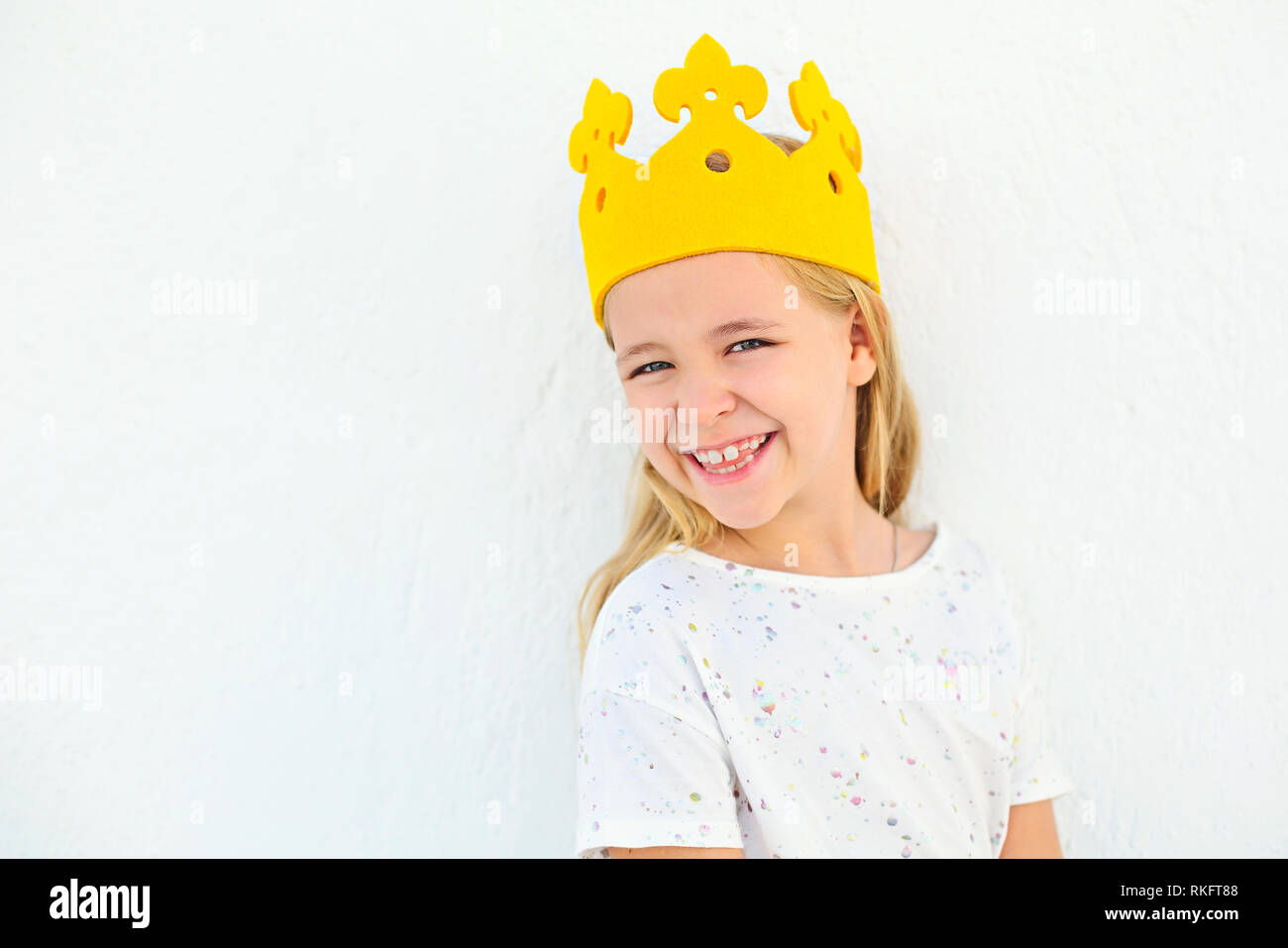 Cute little girl with blonde hair. Little girl with a crown on her head on a white background. Birthday girl Stock Photo