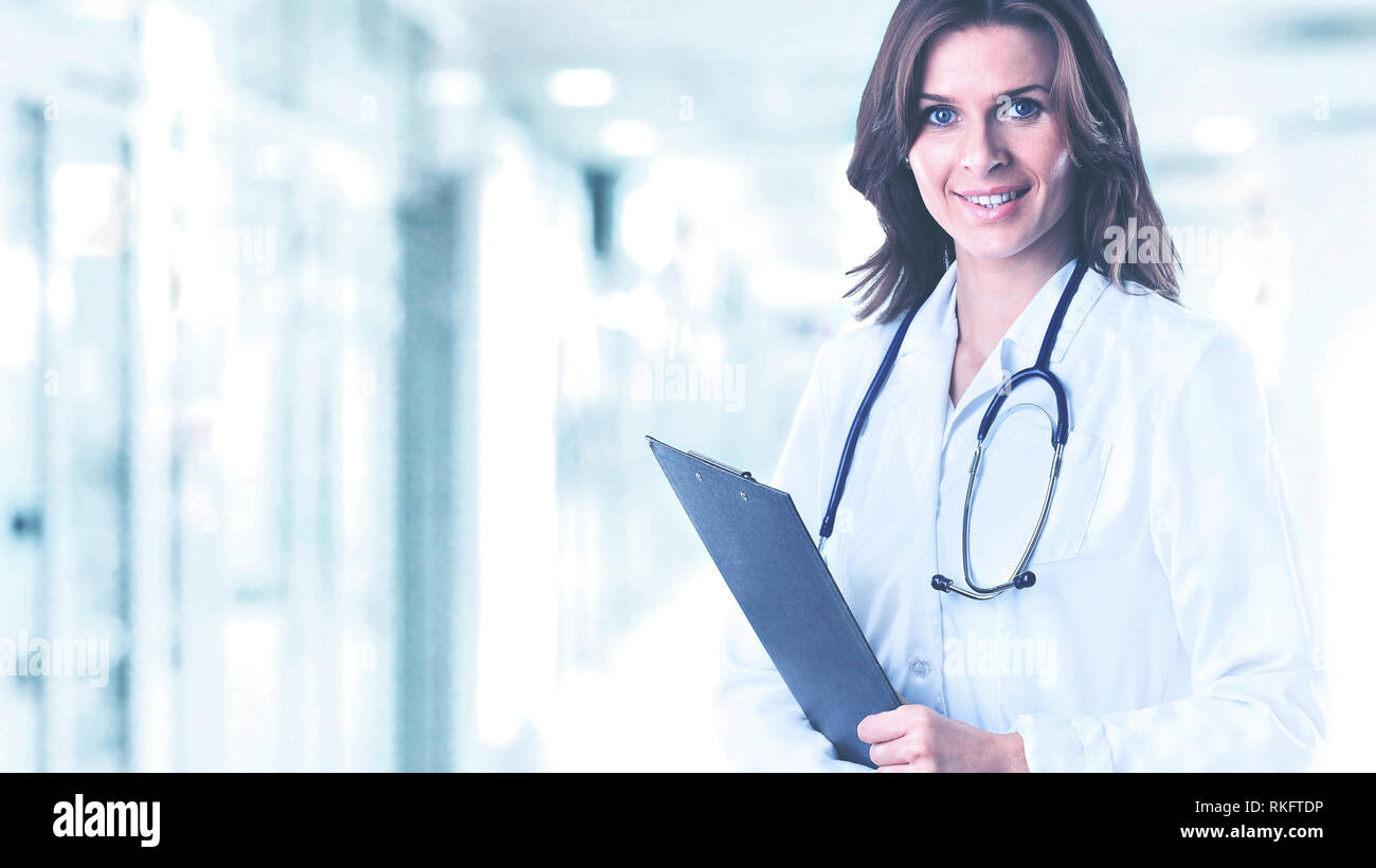 Smiling medical doctor woman with a folder in hospital on background of  bright hall Stock Photo - Alamy