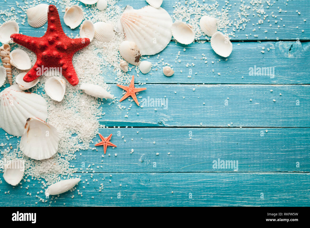summer background red starfish and seashells on blue wooden background Stock Photo