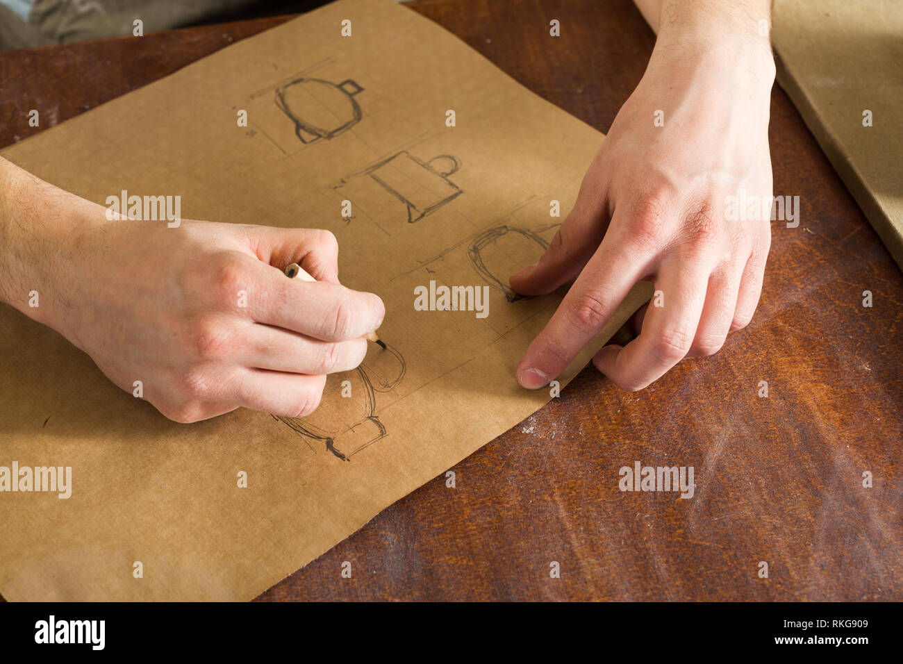 the hand of a man sketching dishes on crafting paper with a pencil, handcrafted work. horizontal picture. Close up Stock Photo