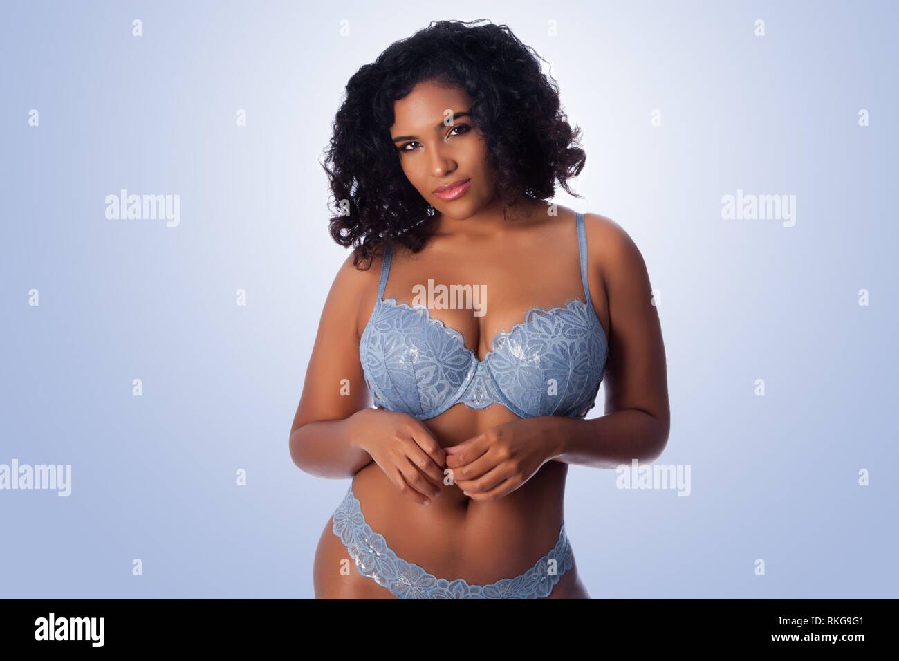 Beautiful happy plus size sexy woman with curly hair in light blue lingerie  bra and thong underwear Stock Photo - Alamy