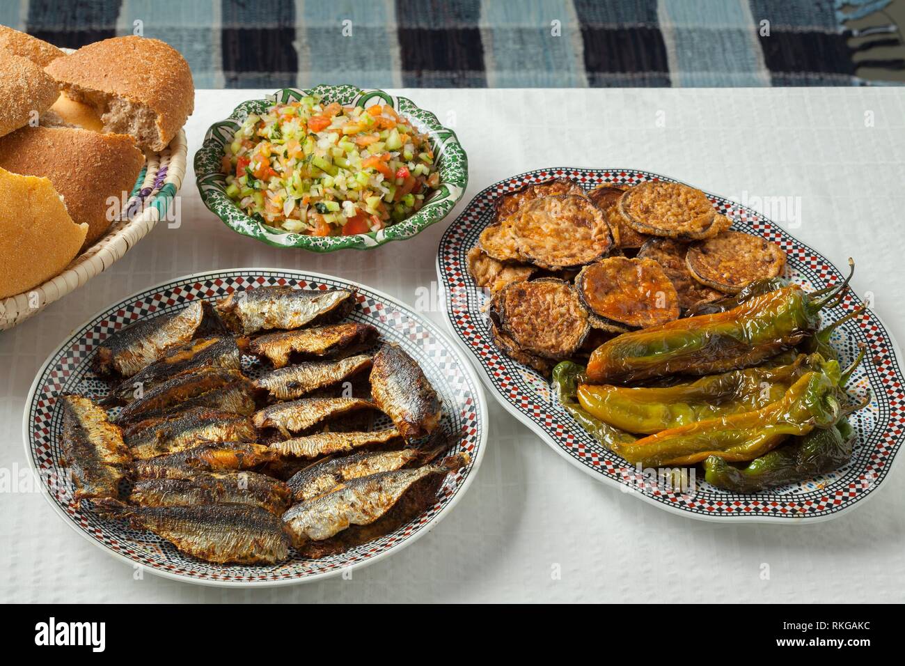 Moroccan meal with stuffed sardines, dishes with vegetables and a basket with bread. Stock Photo