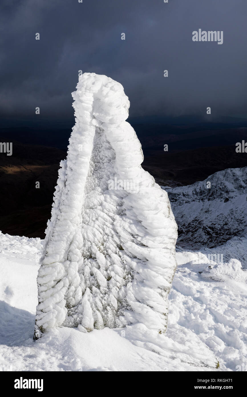 Ice covered marker stone at top of Watkin Path on Mount Snowdon in winter snow in Snowdonia National Park. Rhyd Ddu, Gwynedd, North Wales, UK, Britain Stock Photo