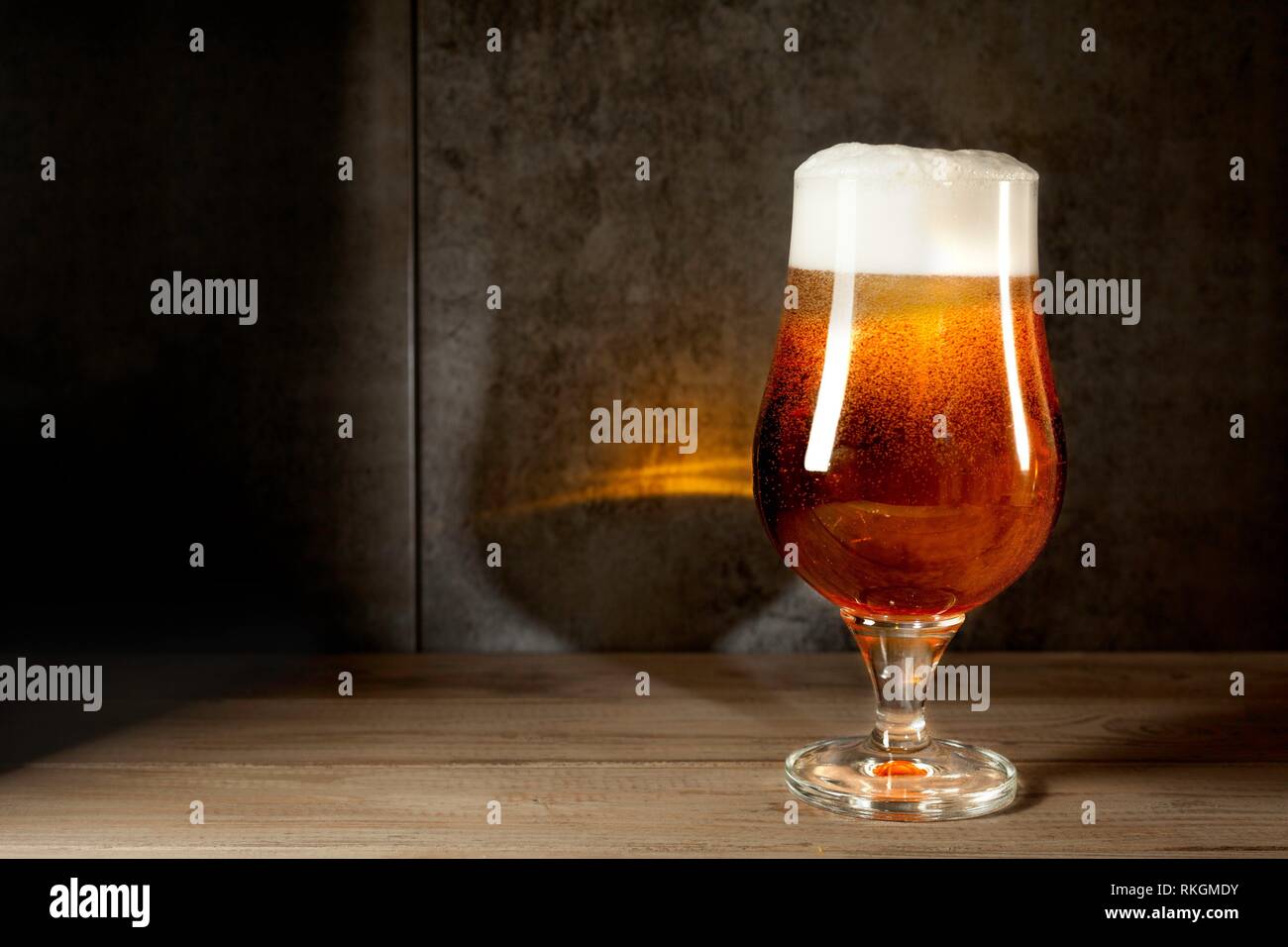 Ale beer cup with foam on wood table and metallic background in twilight and reflection Stock