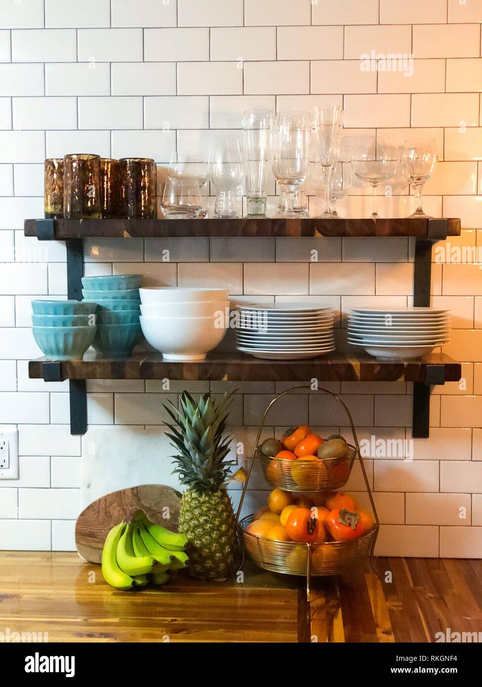 Open butcher block shelving against a tile backsplash wall in the kitchen of a luxury house remodel and renovation. Stock Photo