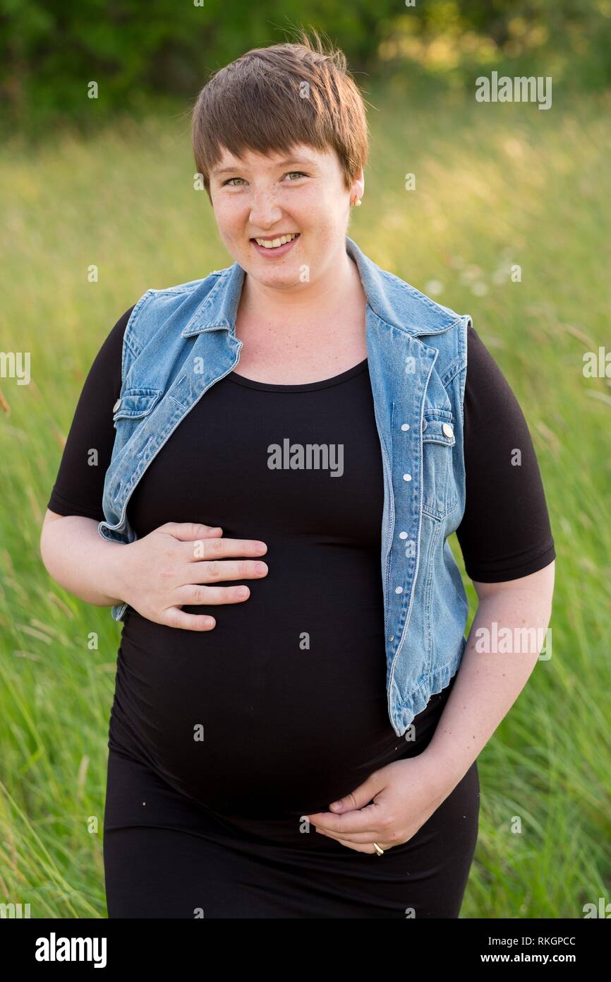 Maternity photo of a young woman with a short hair pixie cut in her third trimester with child
