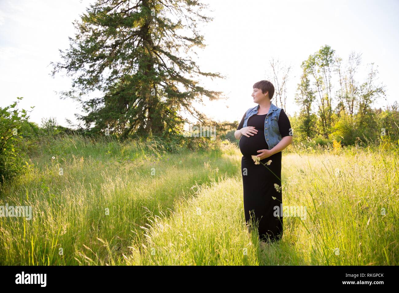 Maternity photo of a young woman with a short hair pixie cut in her third trimester with child. Stock Photo