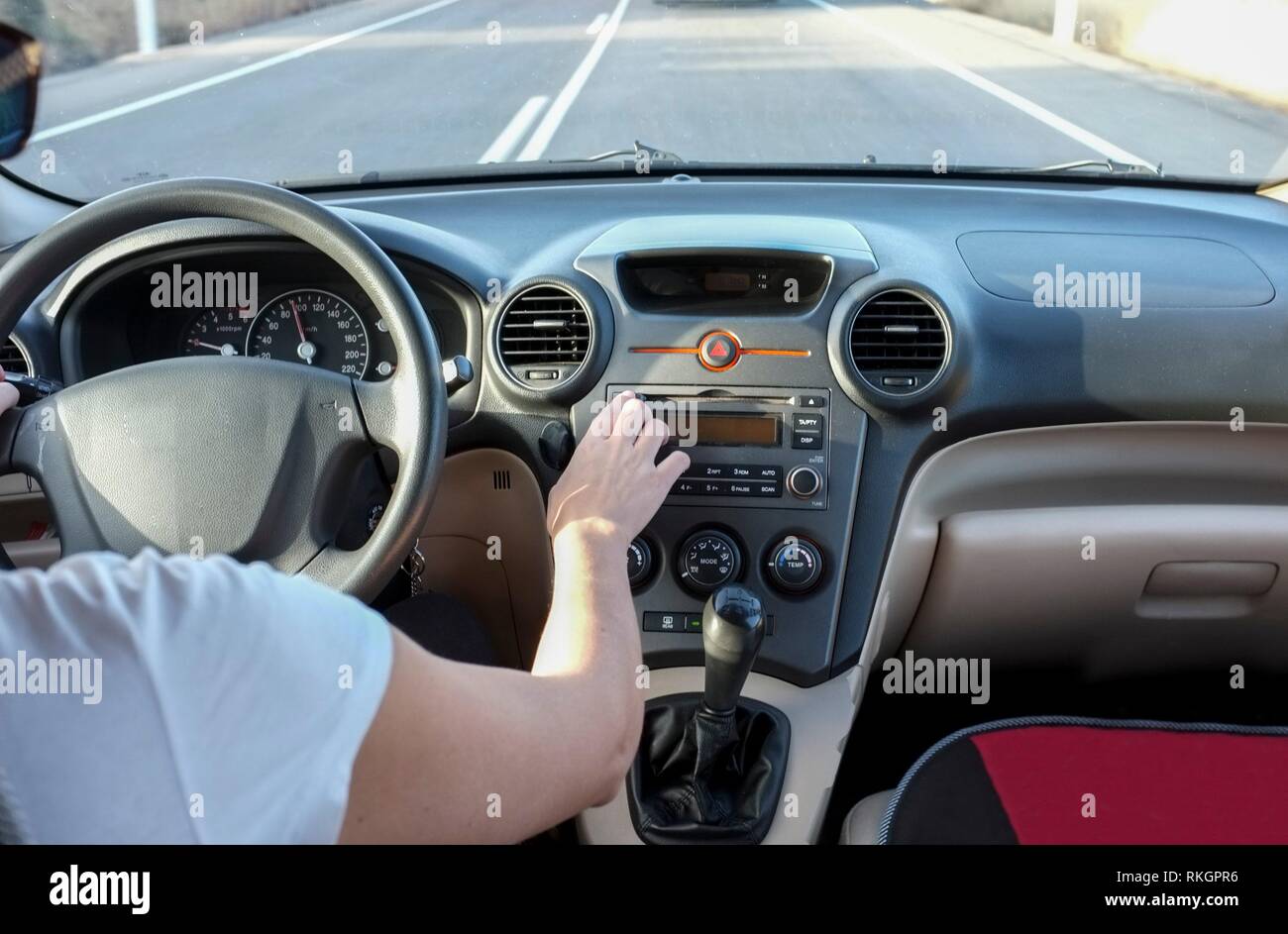 Woman pressing CD Audio eject button while she is driving. Cause of Distracted Driving Accidents concept. Inside car view. Stock Photo