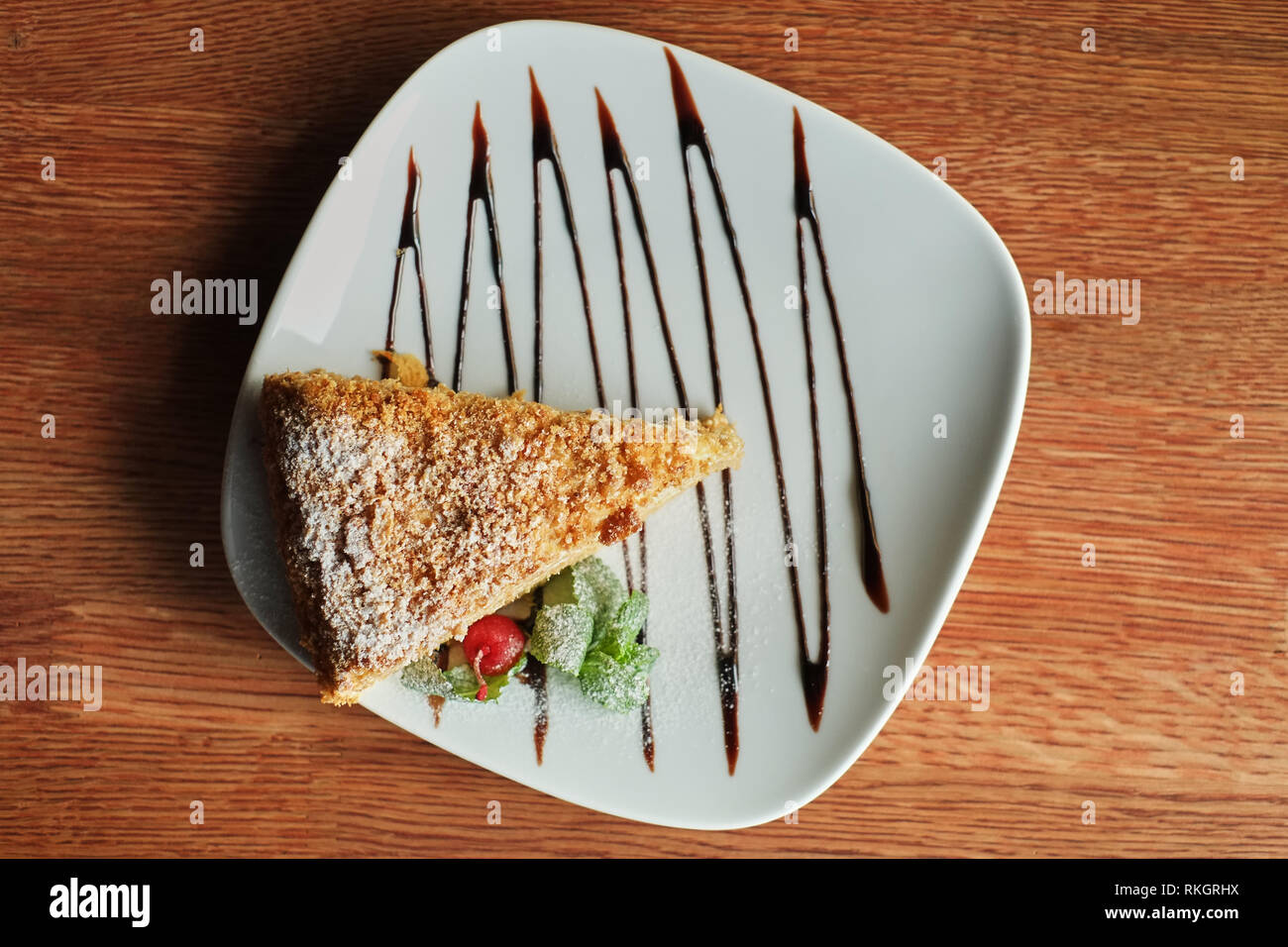 a piece of poured honey cake with chocolate topping on a plate, top view Stock Photo