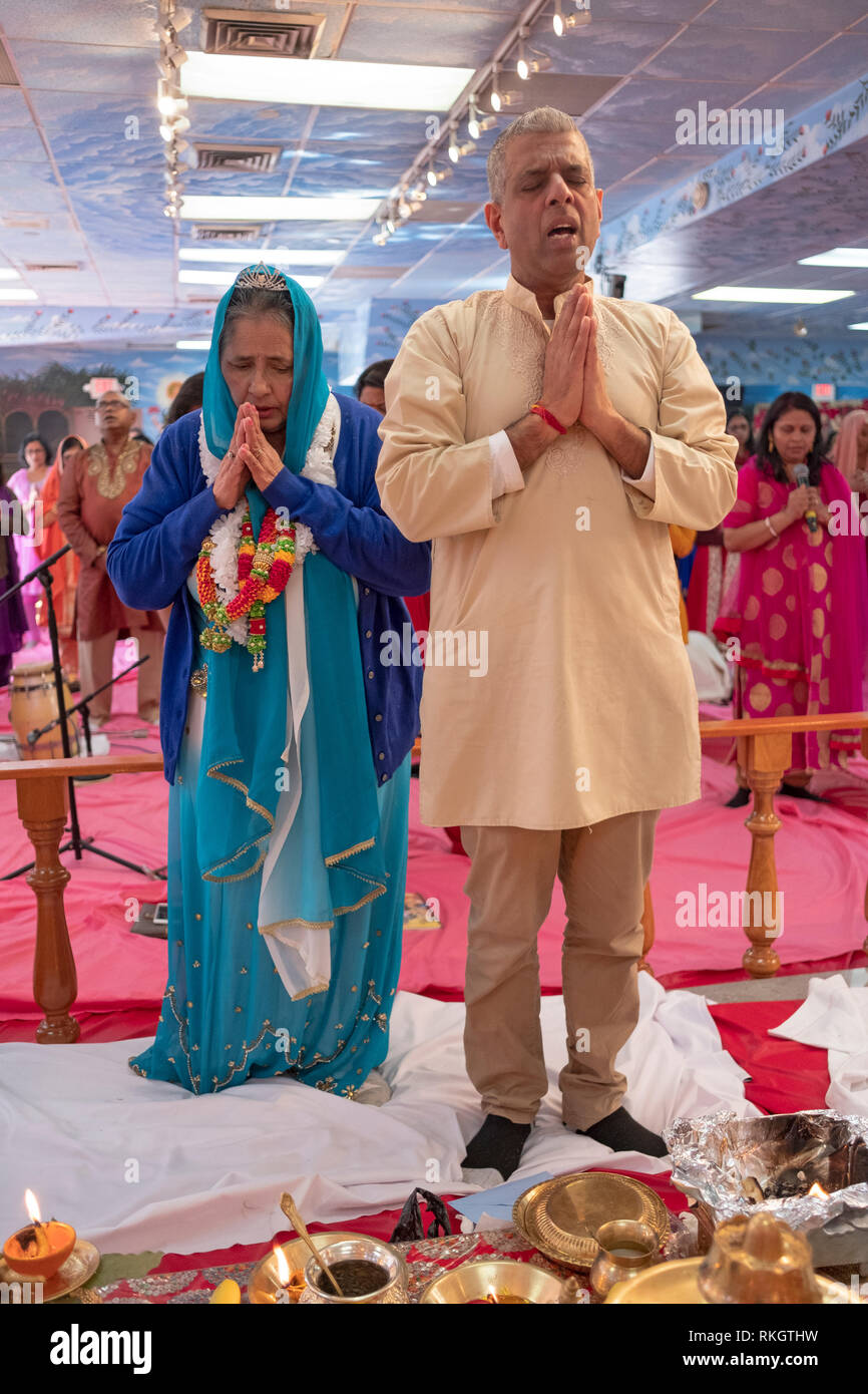 A 70 year old Hindu woman, accompanied by her son, celebrates her birthday by assisting in in the Sunday morning services. In Hollis, Queens, NYC. Stock Photo