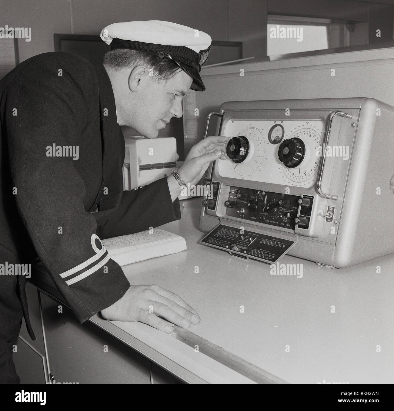 1960s, uniformed male officer on a Union-Castle steamship, using an automatic direction finder (ADF), a marine radio-navigational instrument that automatically and continously displays the relative bearing of the ship to a suitable radio station, technology that was developed in the 1960s. Stock Photo