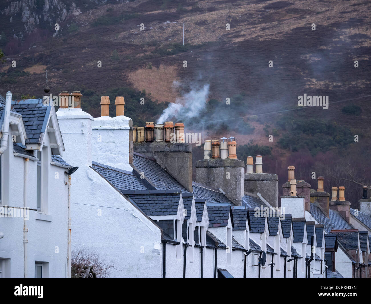 Smoke and domestic chimneys on a row of terraced houses in Shore Street, Ullapool, Highland, Scotland Stock Photo