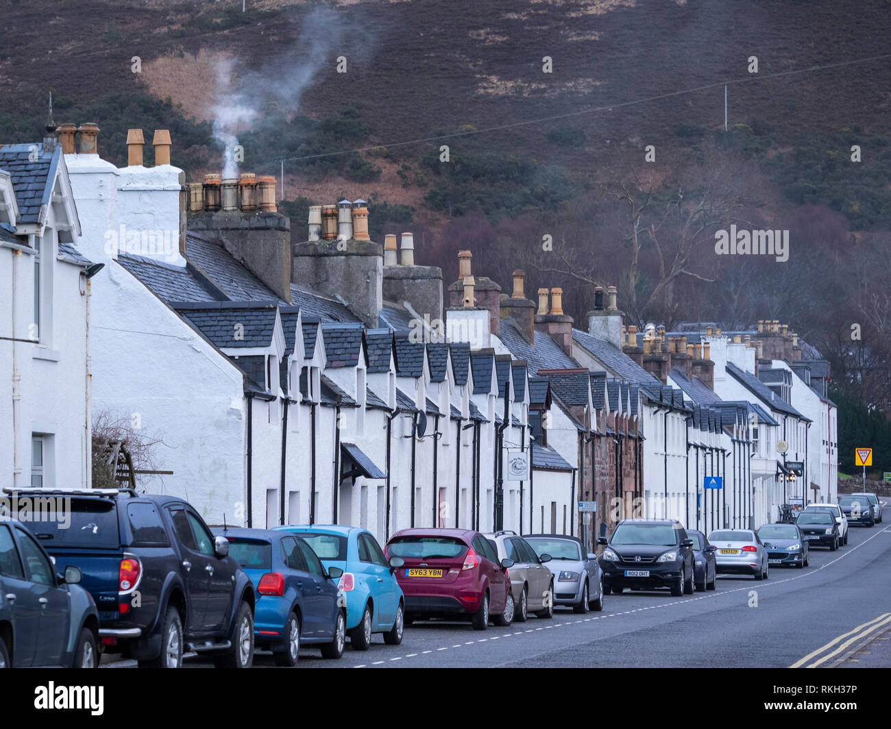 Parked cars and terraced houses in Shore Street on the waterfront at Ullapool, Highland, Scotland Stock Photo
