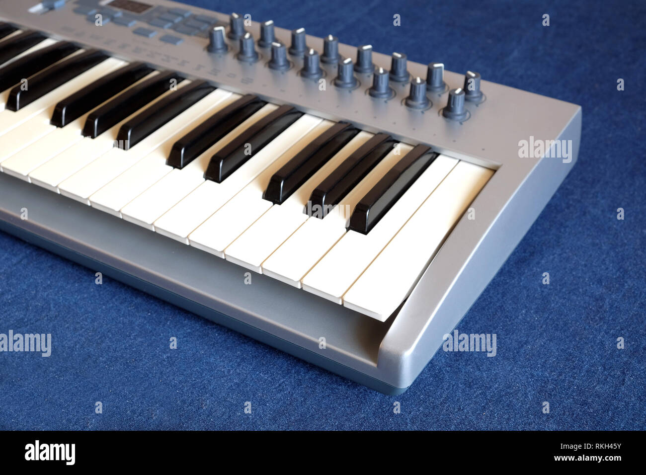 Electronic synthesizer keyboard with many control knobs on denim
