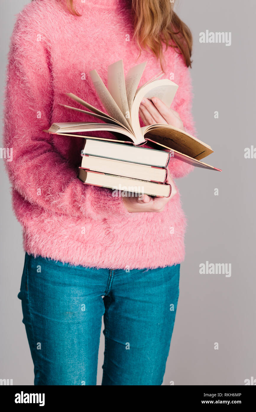 Young girl holding a few books. Teenager girl wearing pink sweater and blue  jeans. Vertical photo Stock Photo - Alamy