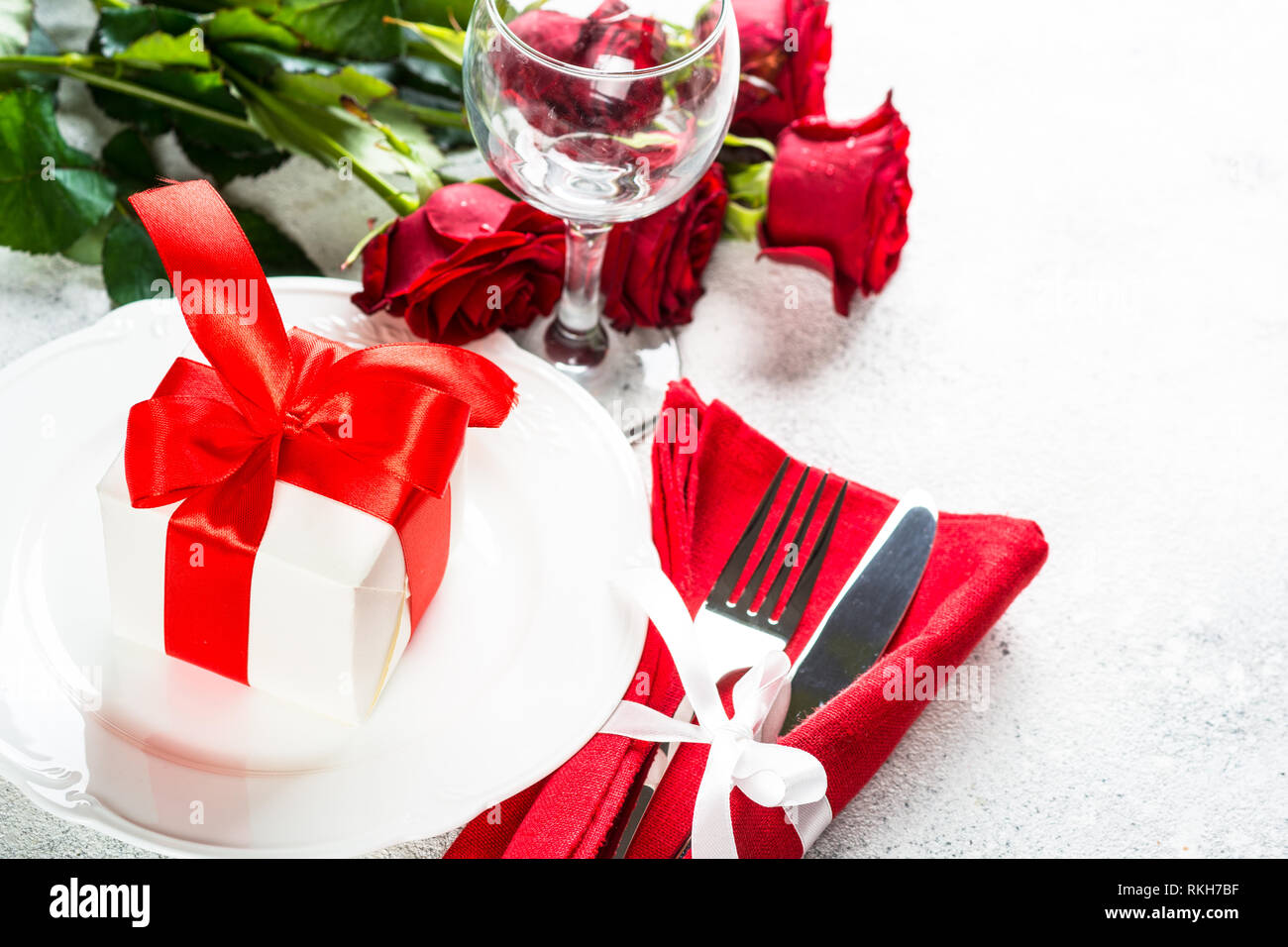 Holiday table setting with plate, roses and present. Stock Photo