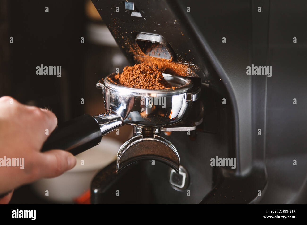 Barista grinding coffee beans using coffee machine, coffee grinder