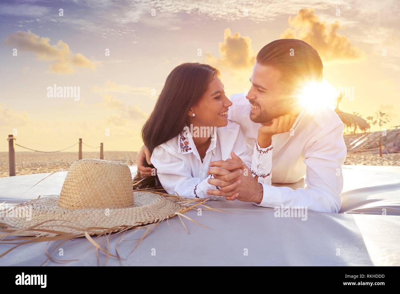 Couple young on beach lounge sunset vacation. Stock Photo