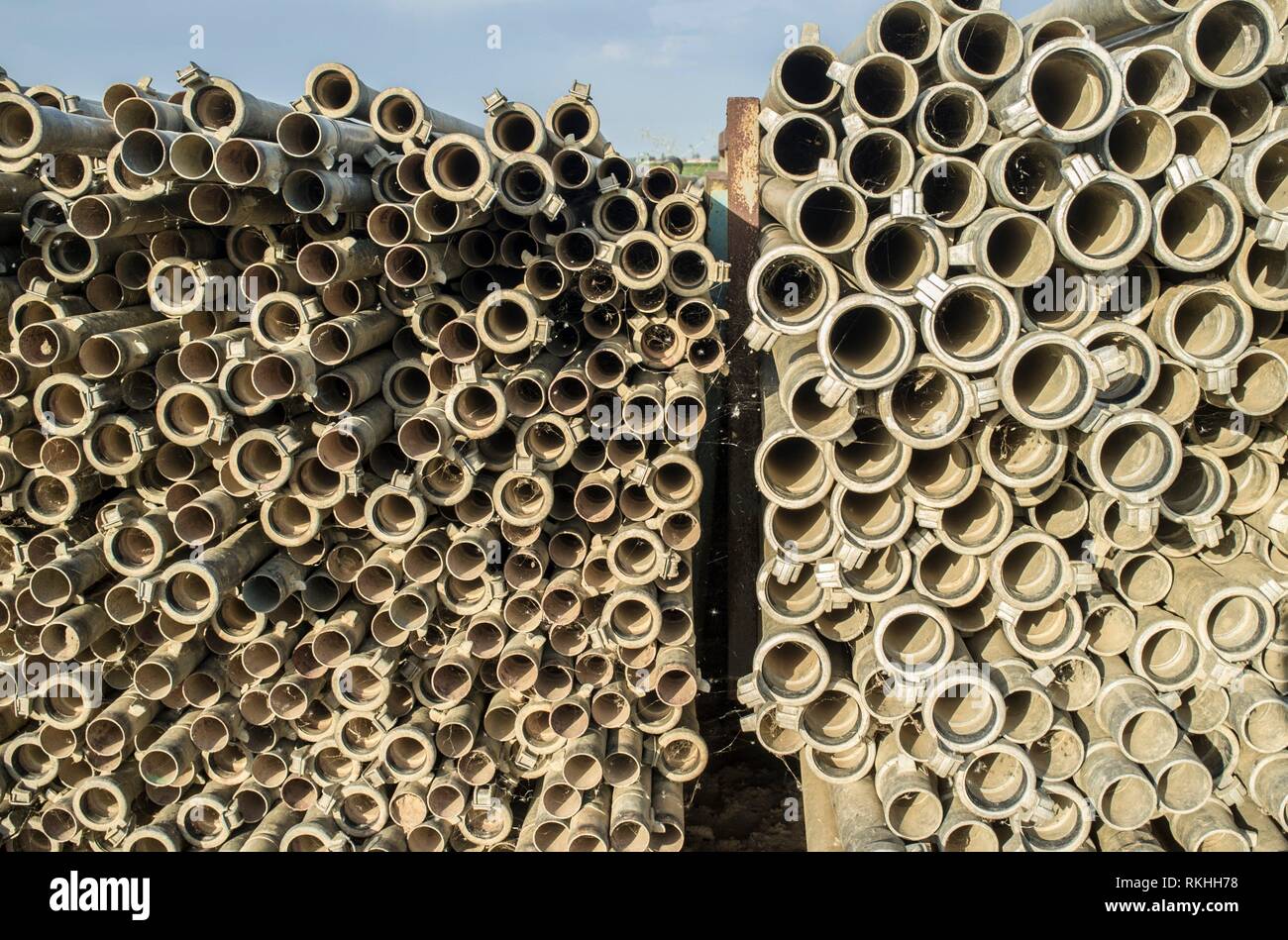 Irrigation metal pipes stacked outdoors out of watering season. Last sunset rays. Stock Photo