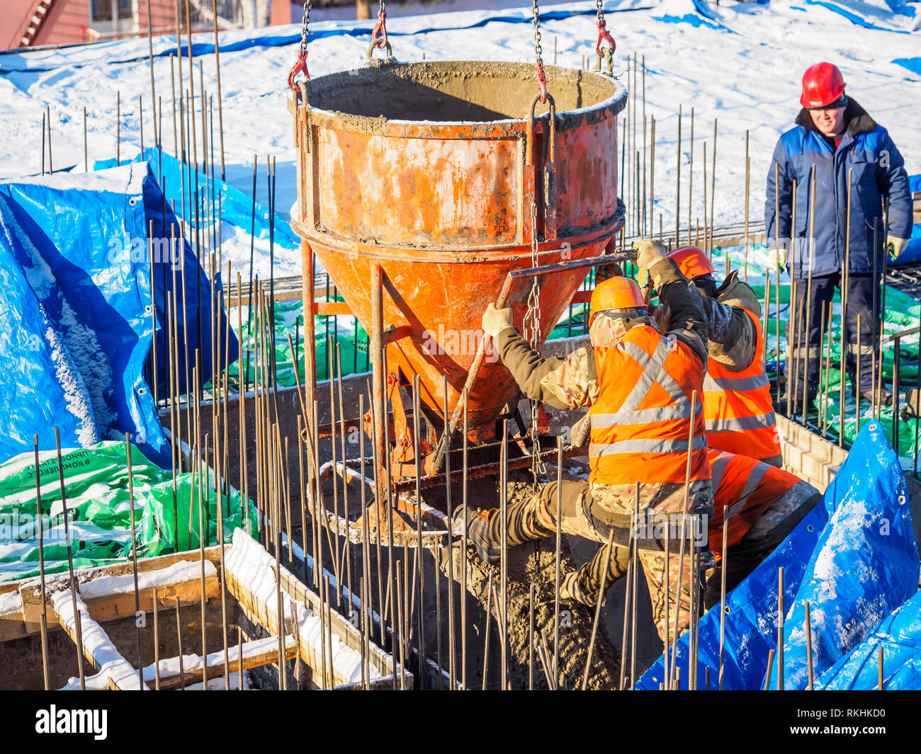 Workers use concrete bucket pouring wet concrete into formwork. Snow