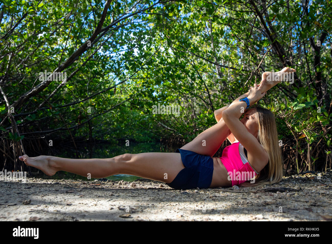 Young woman practicing yoga (Modified Reclining Hands to Leg Pose) in a natural setting - Fort Lauderdale, Florida, USA Stock Photo
