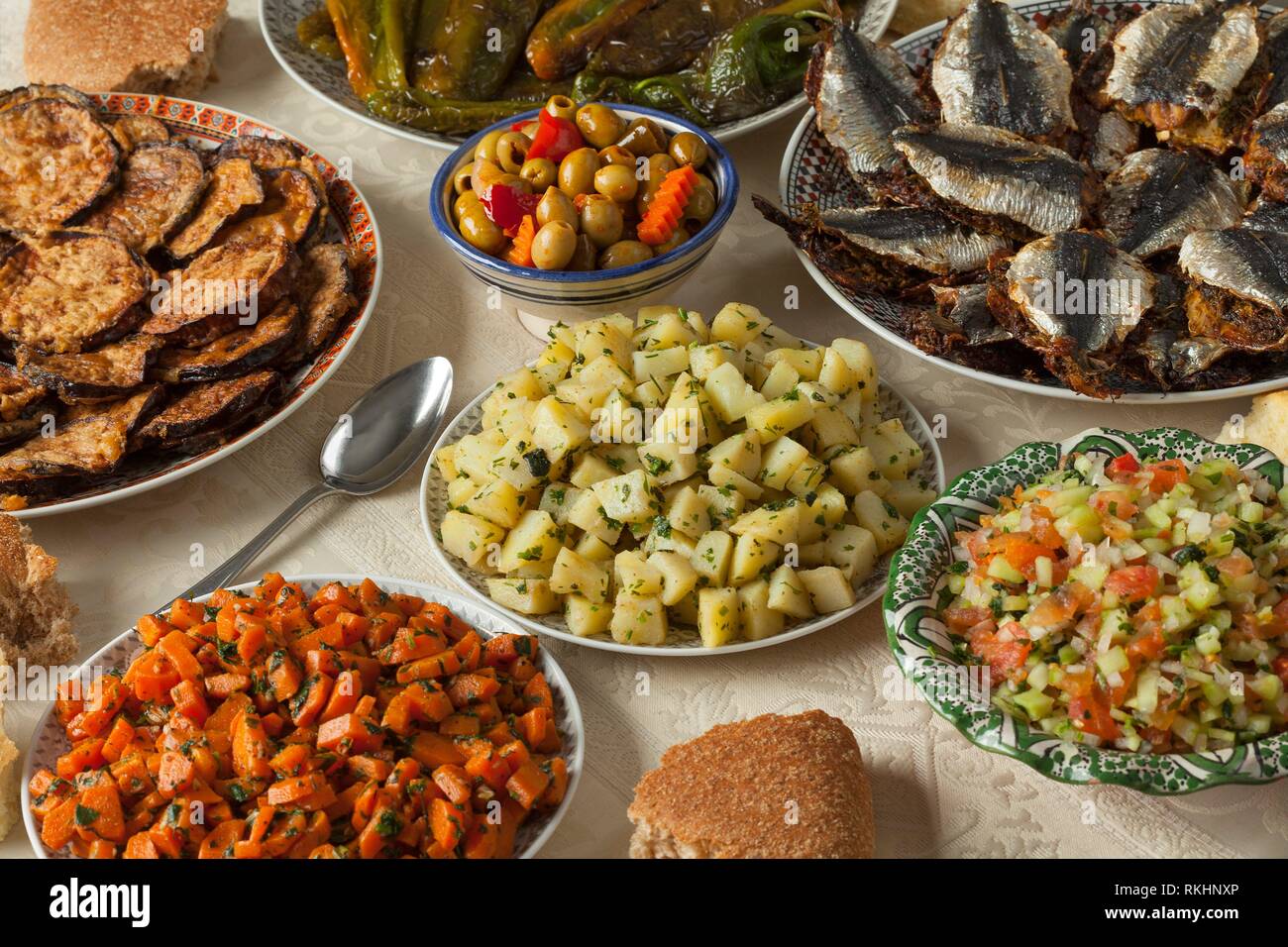 Moroccan meal with a variety of dishes with fresh cooked sardines, vegetables and bread. Stock Photo