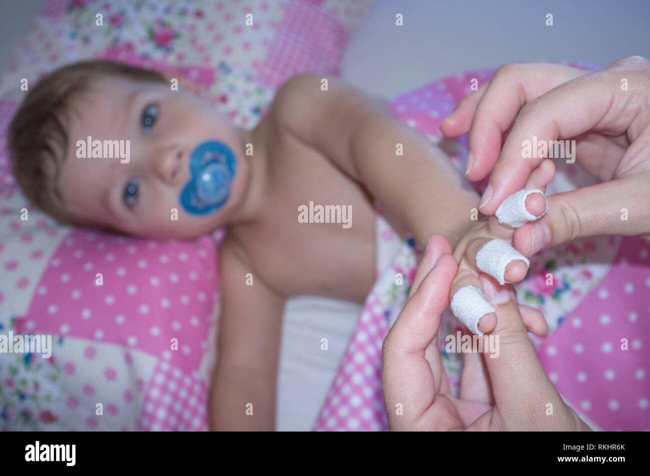 Baby boy shows his bandaged fingers before suffering a domestic accident. Domestic accidents concept. Stock Photo