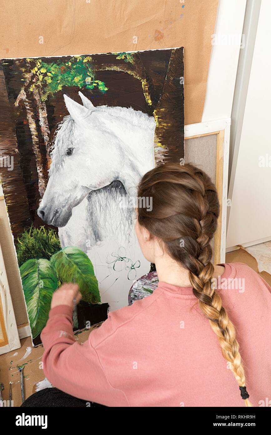 Young girl painting a picture of a horse. Vertical view from behind