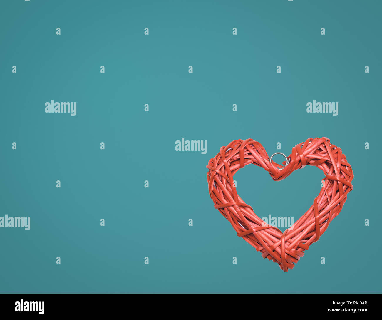 Living coral trendy color of the year 2019 heart shaped braided wicker on blue background Stock Photo
