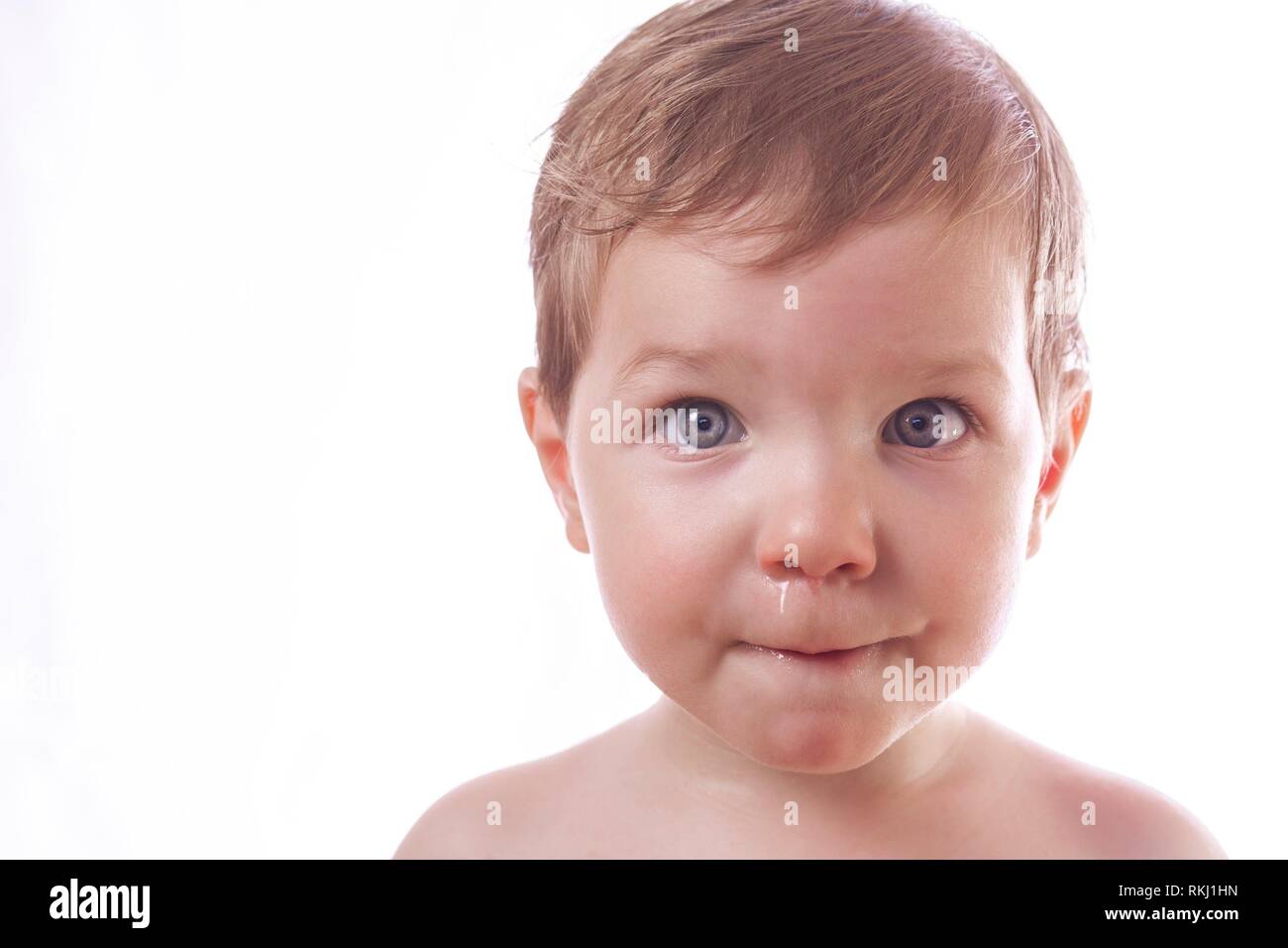 Two years baby boy looking at camera with the nose irritated and full of snot. Isolated over white background. Stock Photo