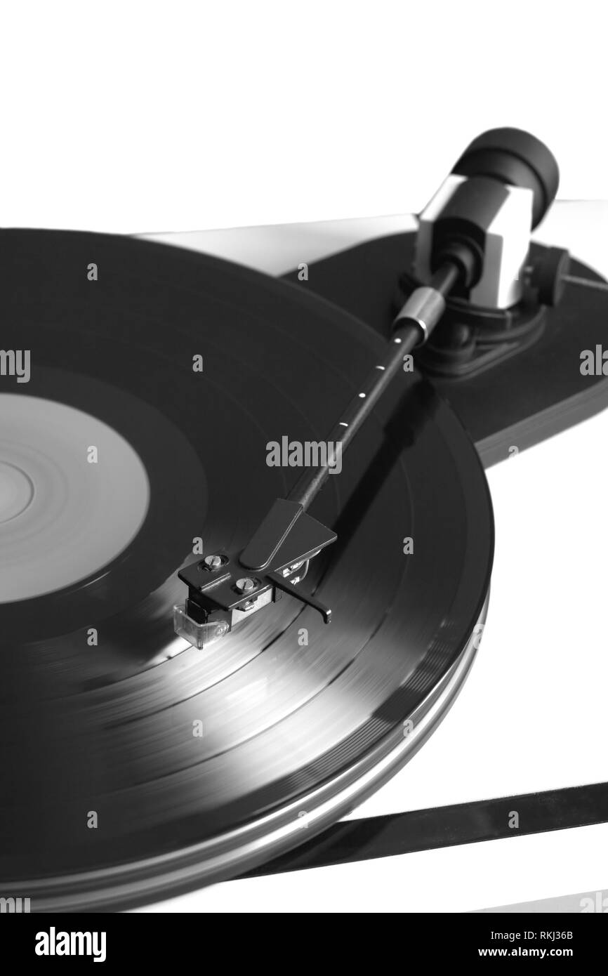 Vintage turntable in silver case playing vinyl record with red label . Vertical black and white photo isolated on white background closeup Stock Photo