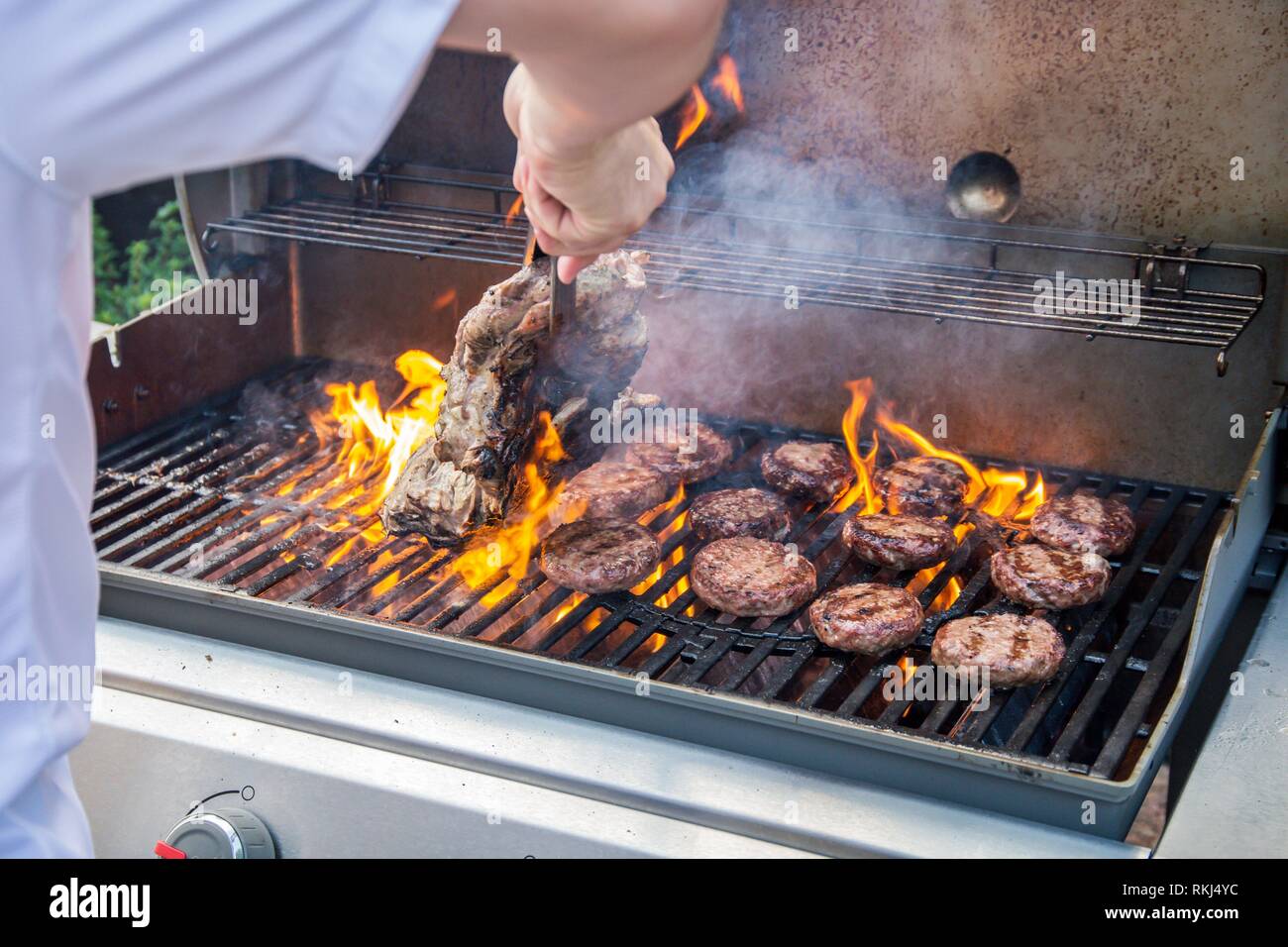 Marinated lamb joint and beef burgers cooking on a barbecue Stock Photo