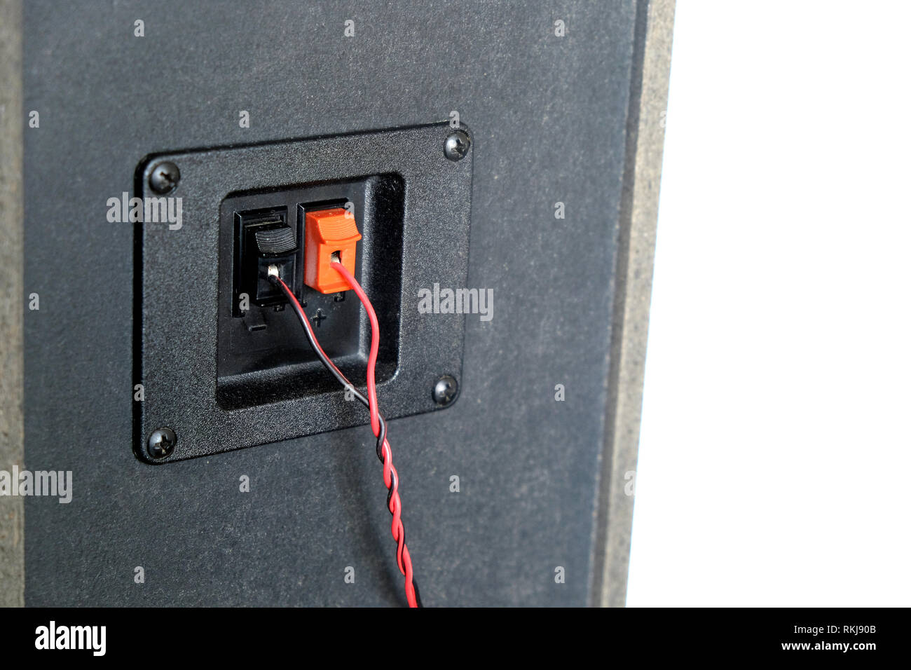 Red and black twisted wire connected to cable connection socket on rear side speaker system box