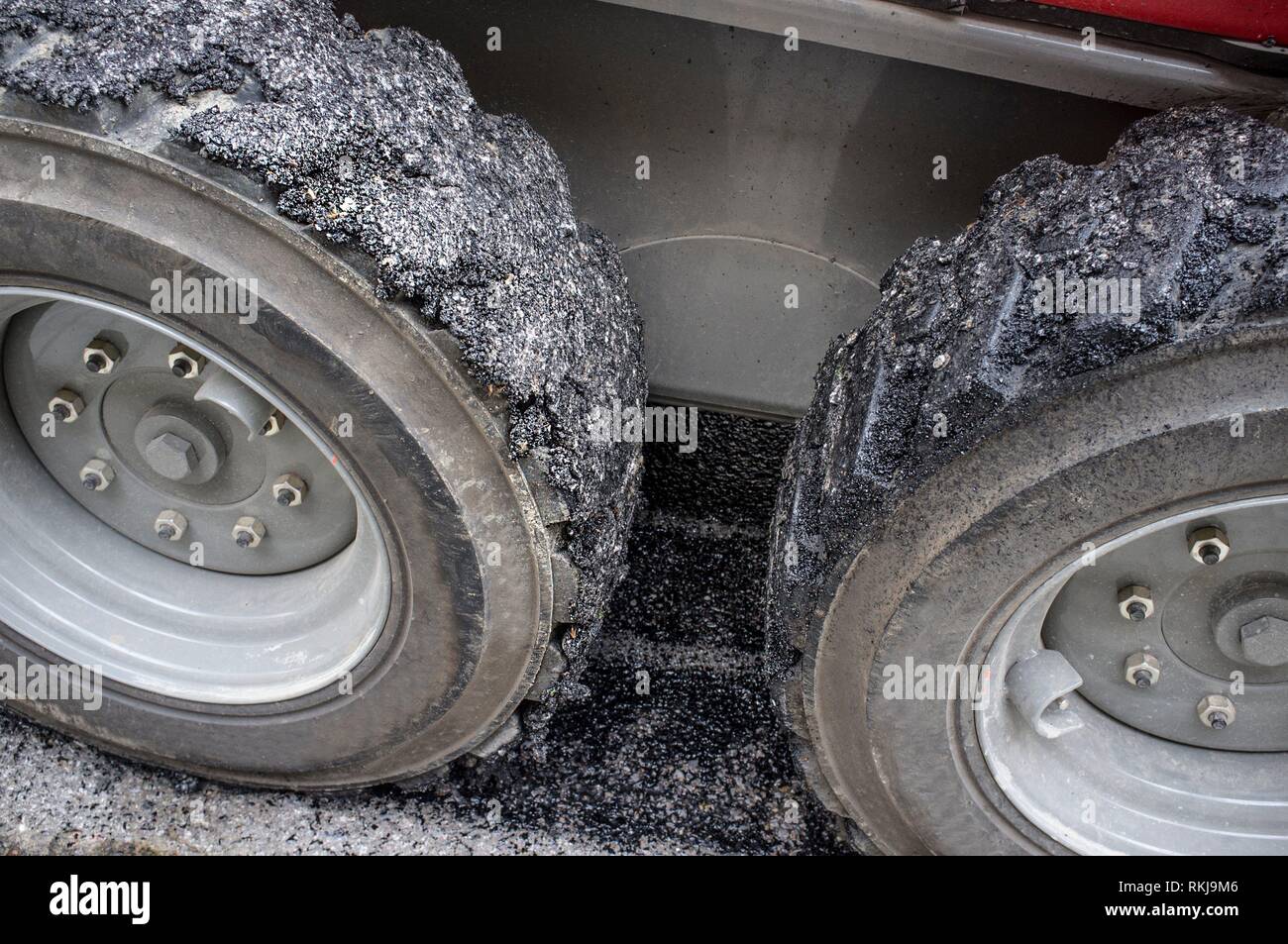 Work on the laying of asphalt in the city. Lifting hook bucket with tires full of tar. Stock Photo