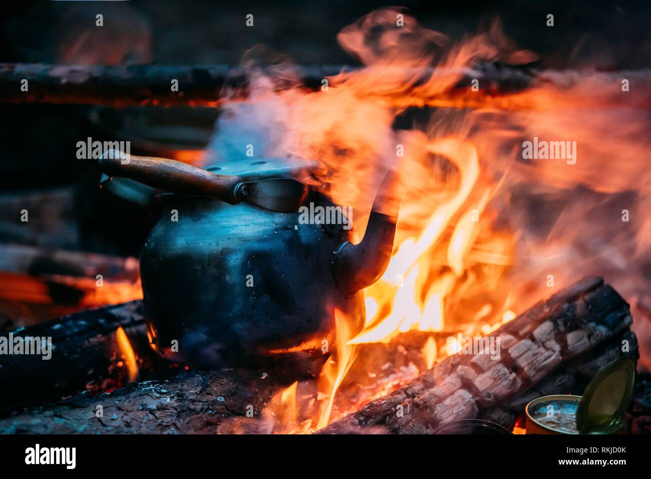 https://c8.alamy.com/comp/RKJD0K/black-old-retro-iron-camp-kettle-boiling-water-on-a-fire-in-forest-bright-flame-fire-of-bonfire-at-dusk-night-RKJD0K.jpg