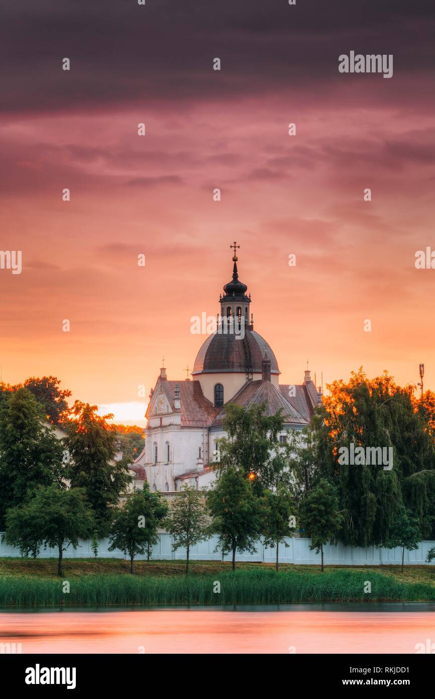 Nesvizh, Minsk Region, Belarus. Corpus Christi Church And Castle Pond Lake At Summer Sunset Evening Or Sunrise Morning. Famous Landmark In Nyasvizh. Stock Photo