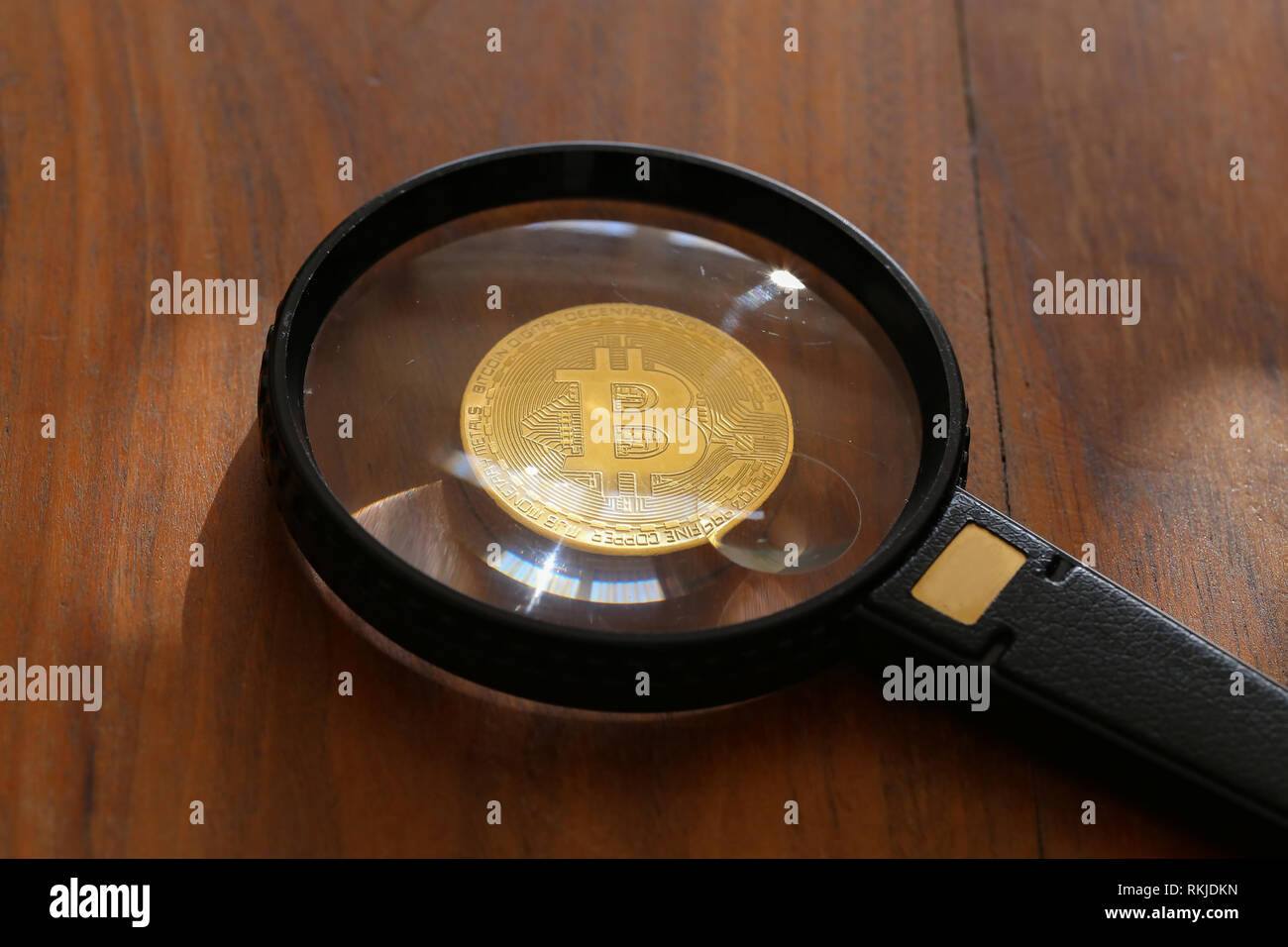 Magnifying glass with gold bar pile of gold coins under it
