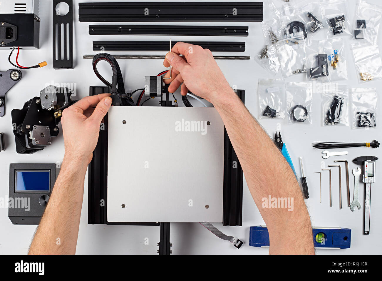 young man student assembly of 3D printer building kit on white table background Stock Photo