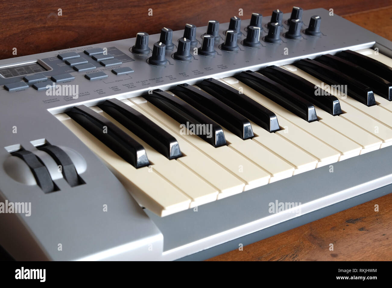 Electronic synthesizer keyboard with control wheels and knobs in silver