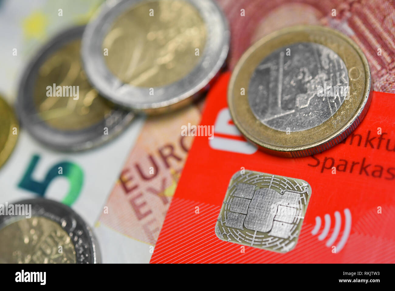 ILLUSTRATION - 08 February 2019, Hessen, Frankfurt/Main: An EC card with integrated NFC technology for cashless payments is on a table together with euro coins and banknotes. On 12.02.2019 the Bundesbank presents the study 'Costs of cash payments in retail trade'. Photo: Arne Dedert/dpa Stock Photo