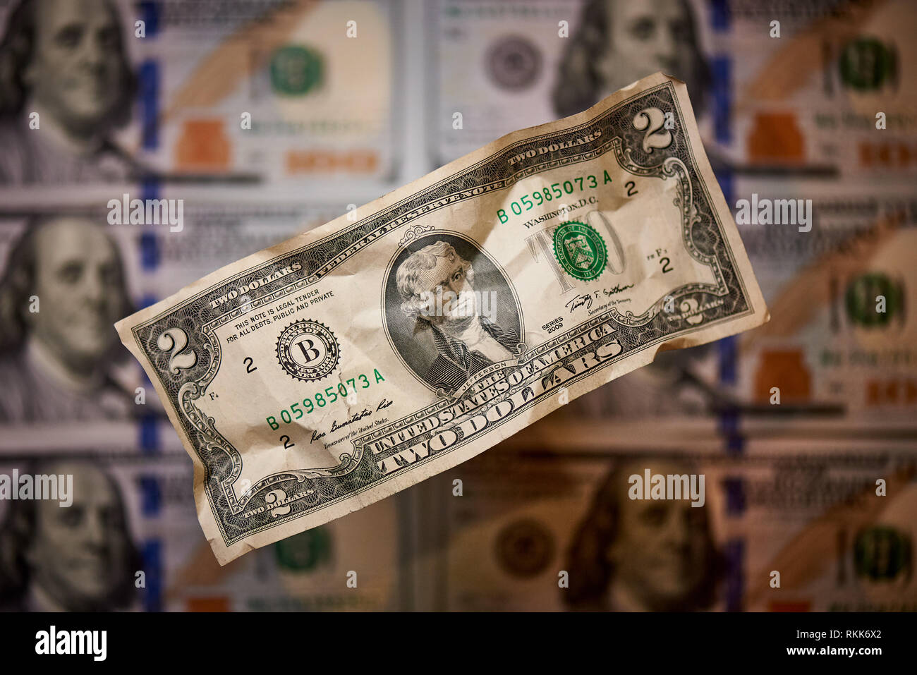 Two crumpled dollars on a blurred background of bills worth one hundred dollars the new American bill. Stock Photo