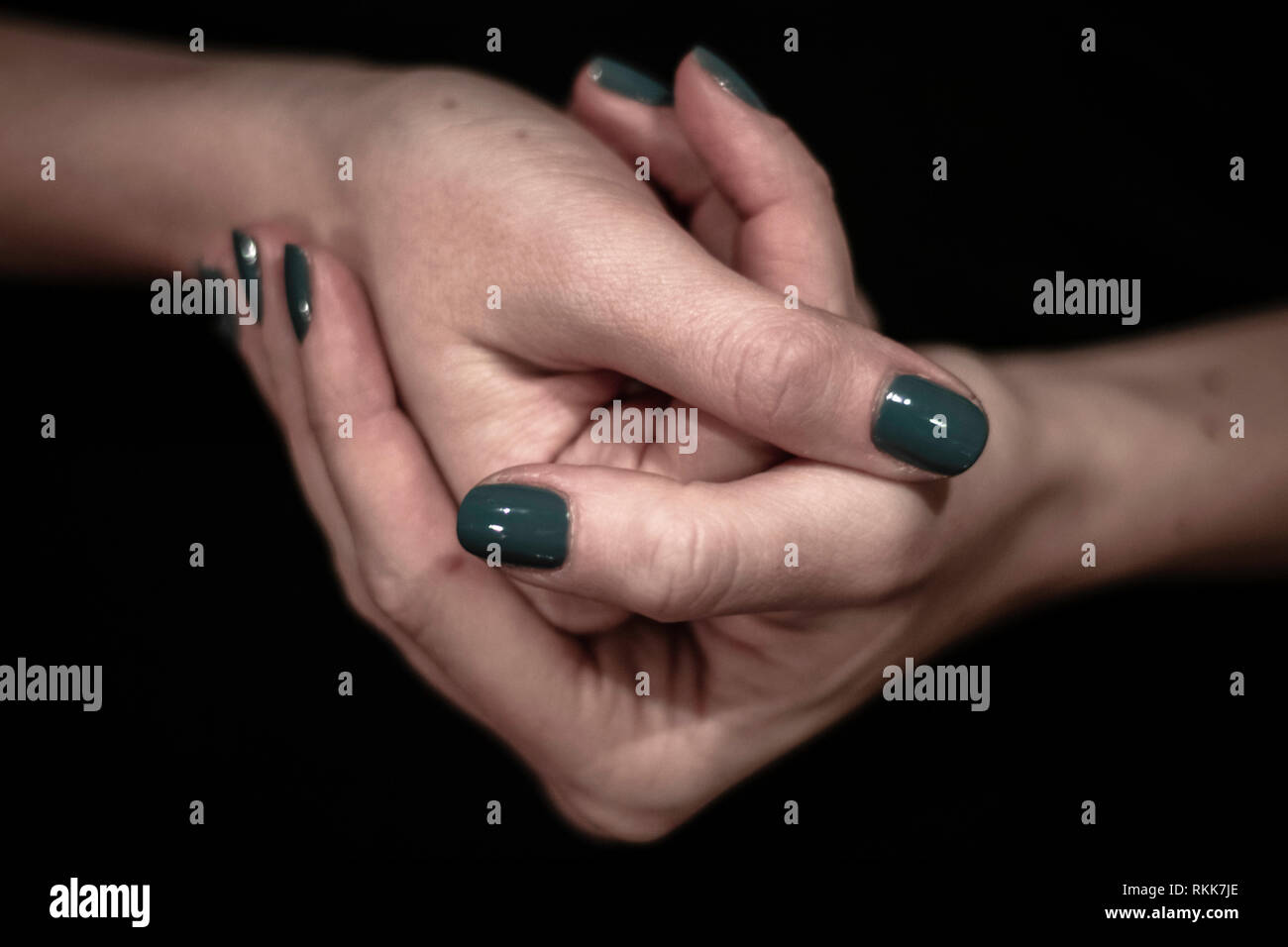 Women hands holding together closeup shot of hands with green painted nails Stock Photo