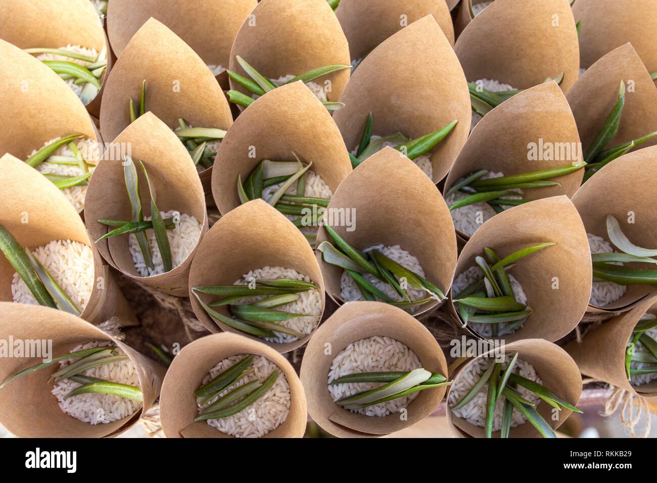 Basket full of cornets filled with rice and olive tree leaves for wedding. Overhead view. Stock Photo