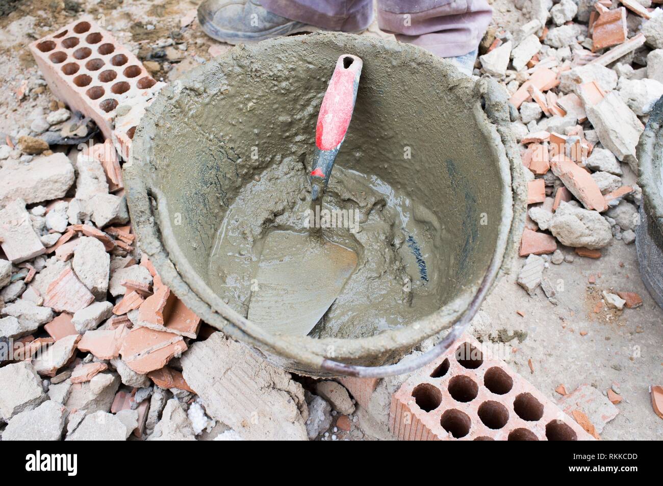 Empty plaster bucket over brick rubble. Overhead shot. Stock Photo