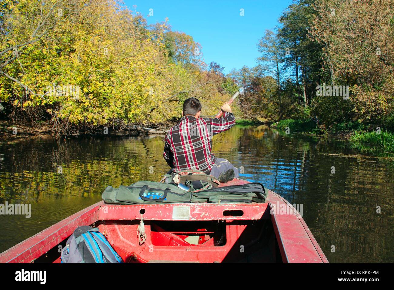 Fisherman sailing on boat on river in autumn. Fisherman with paddle