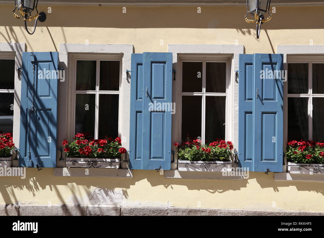 Red flowers on the windowsill / Windows with shutters Stock Photo