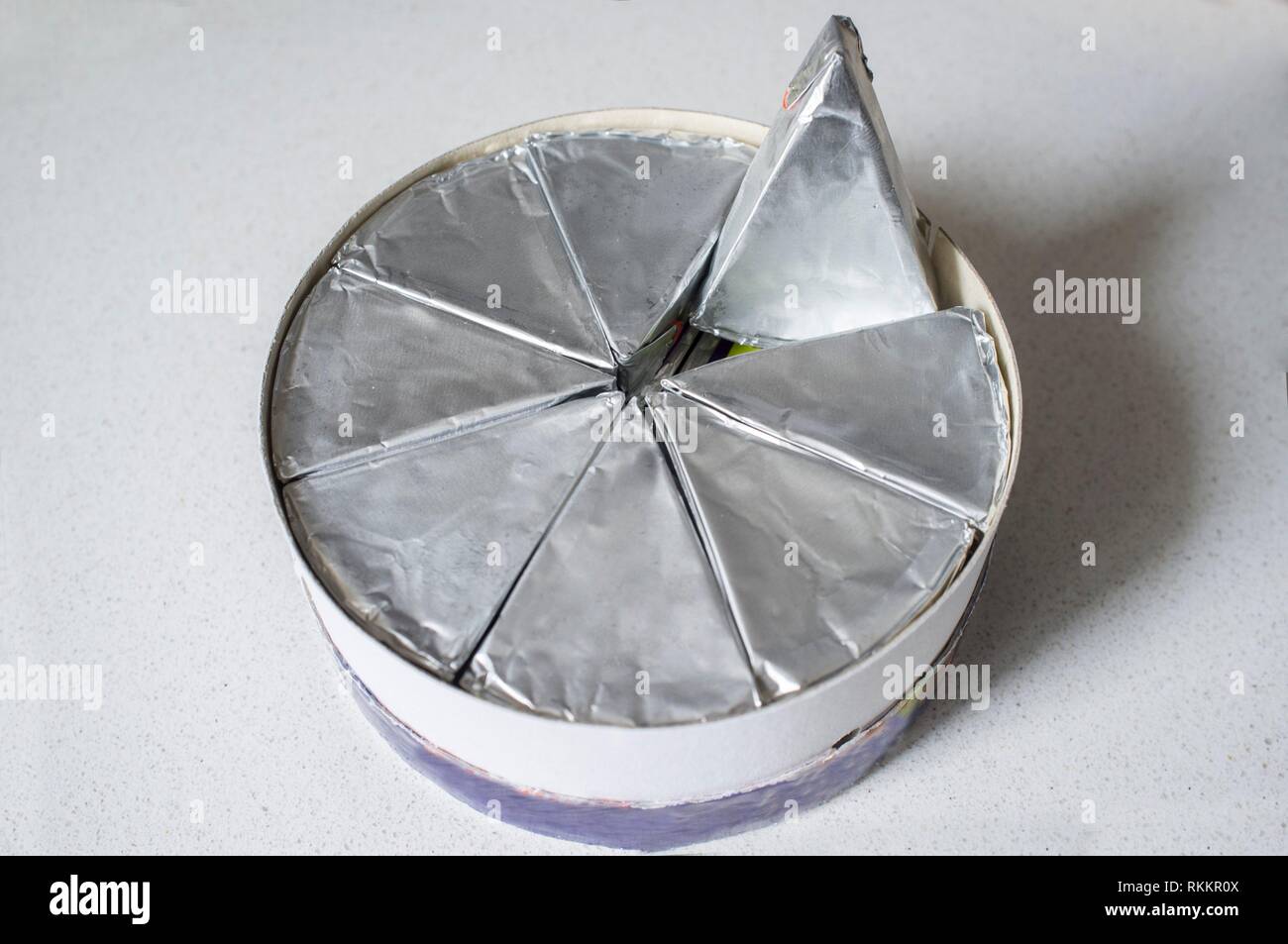Round cardboard box with melted cheese in aluminium foil. Naural light. Stock Photo