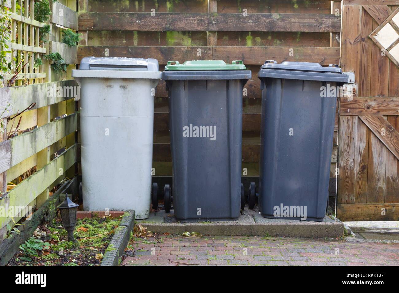 Three rolling trash cans in a dutch garden Separating trash Stock