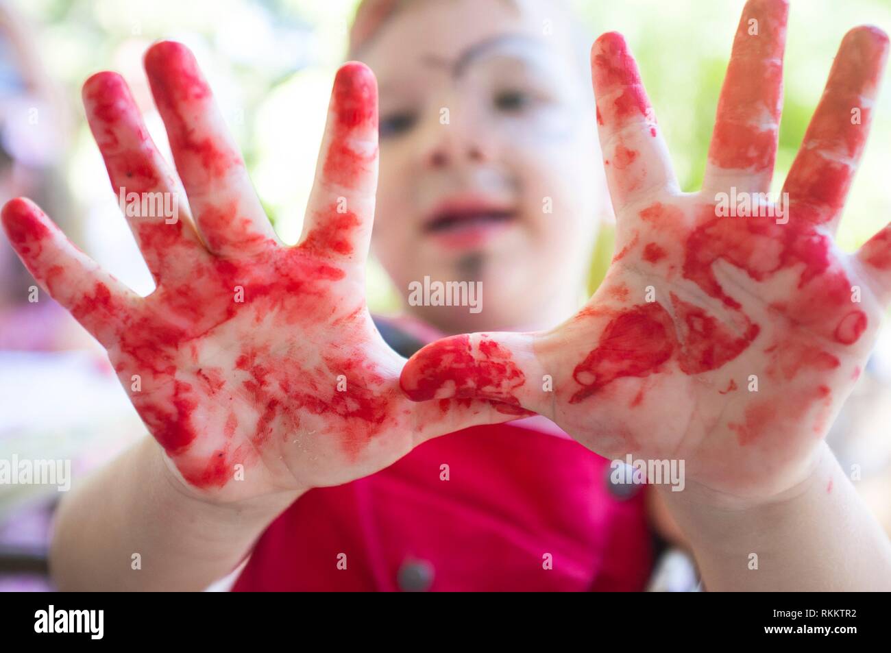 Chid boy showing his red stained hands after arts workshop for children. Closeup. Stock Photo