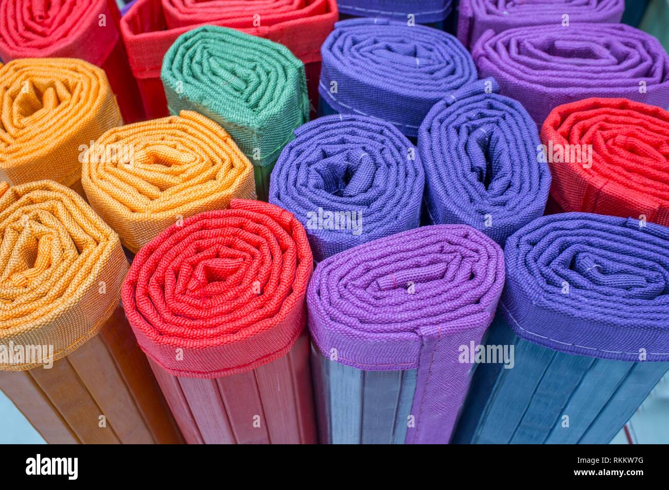 Loads of many rolled colorful light ratan carpets. Closeup. Stock Photo